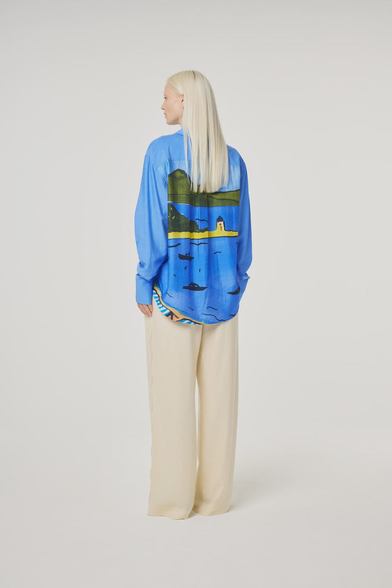 Blue shirt with seaside pattern on the back in yellows and greens