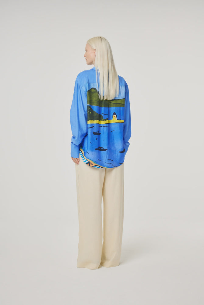 Blue shirt with seaside pattern on the back in yellows and greens